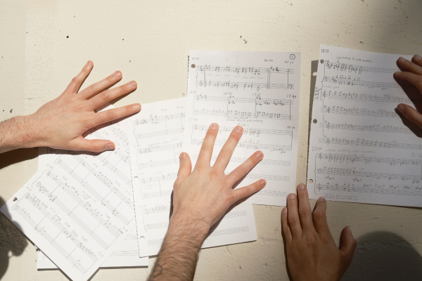 Two pairs of hands handling sheet music